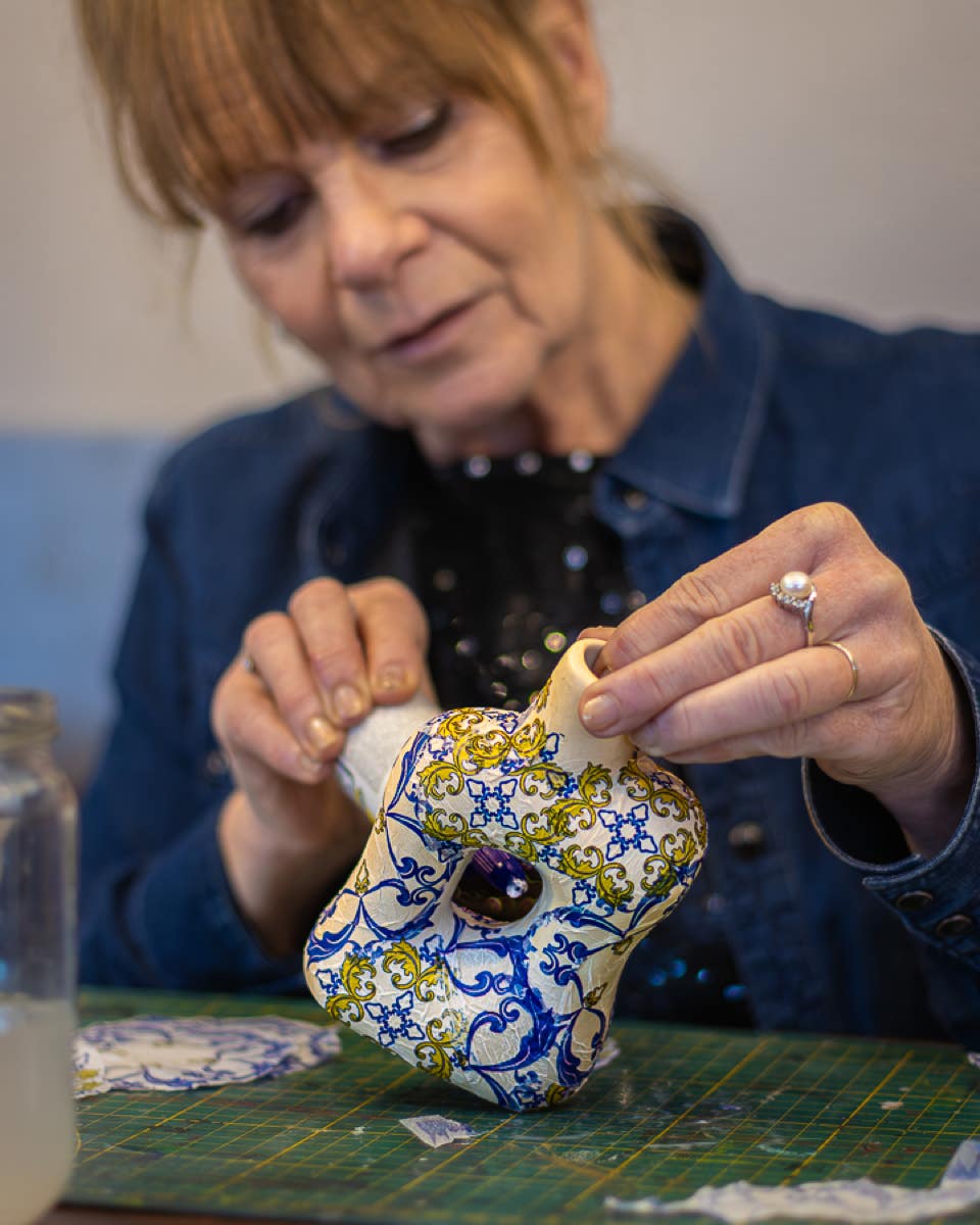 Lisette Boer brengt de decoupage lijm aan op het beeldje, zodat deze een mooi blauw patroon krijgt.