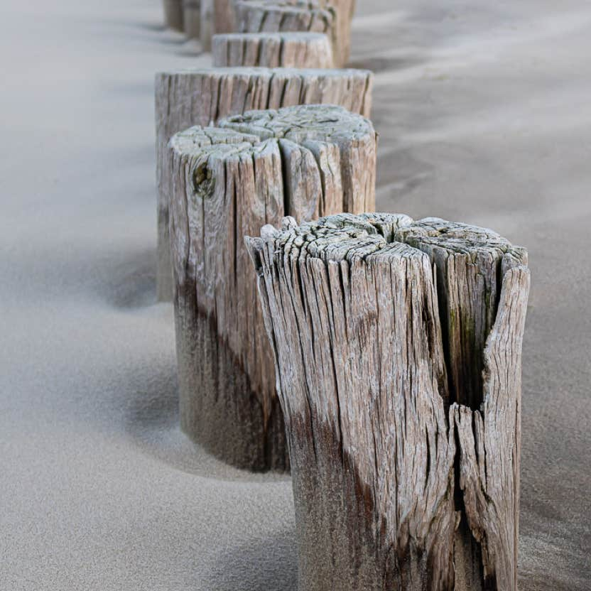 Foto van palen in het zand op het strand.