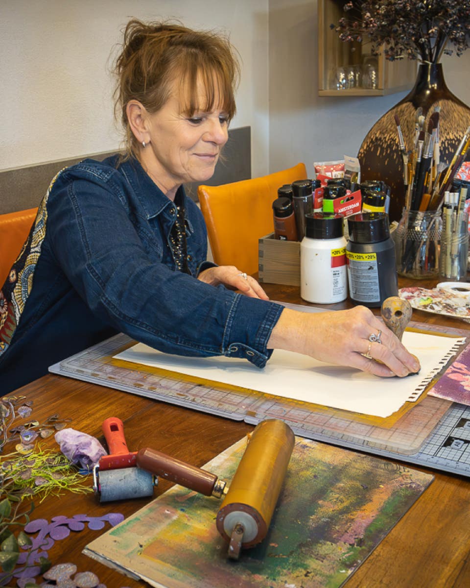 Lisette Boer stampt het papier aan om een nieuwe monoprint te maken.