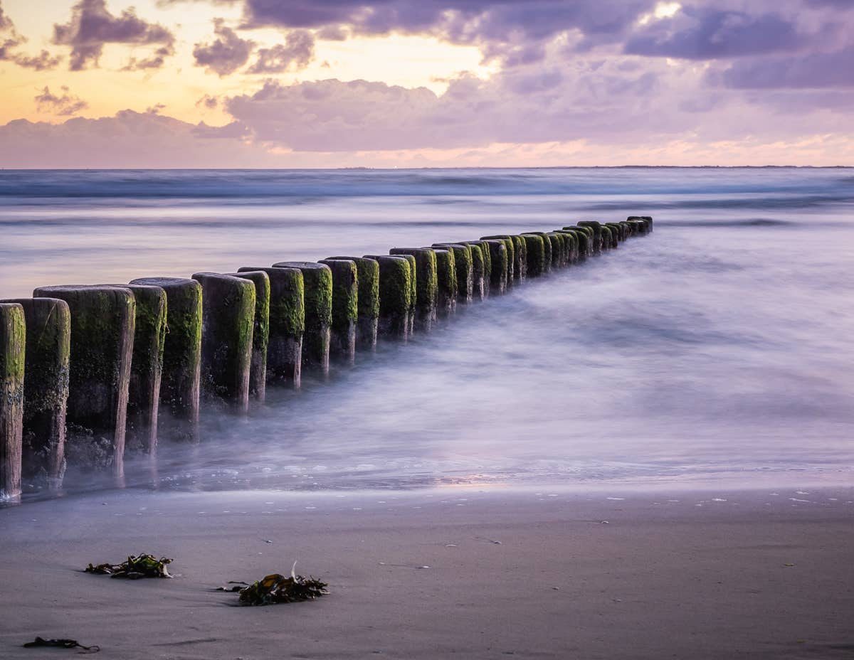 Foto van golfbrekers vanaf het strand de zee in.