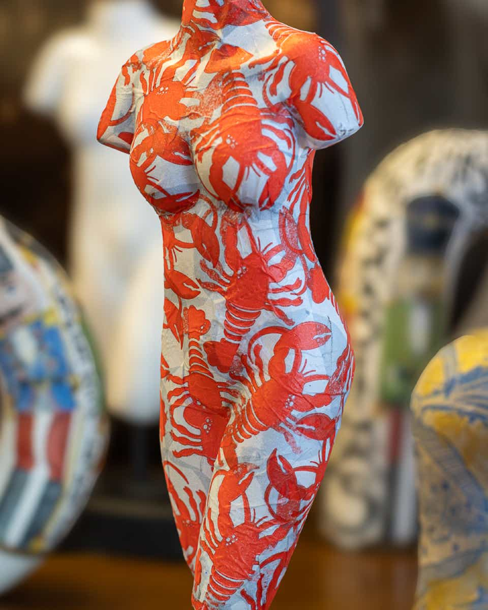 Een van de decoupage kunstwerken van Lisette Boer. Een model van een vrouw bedekt met afbeelding van rode kreeften. Aangebracht door decoupage technieken.