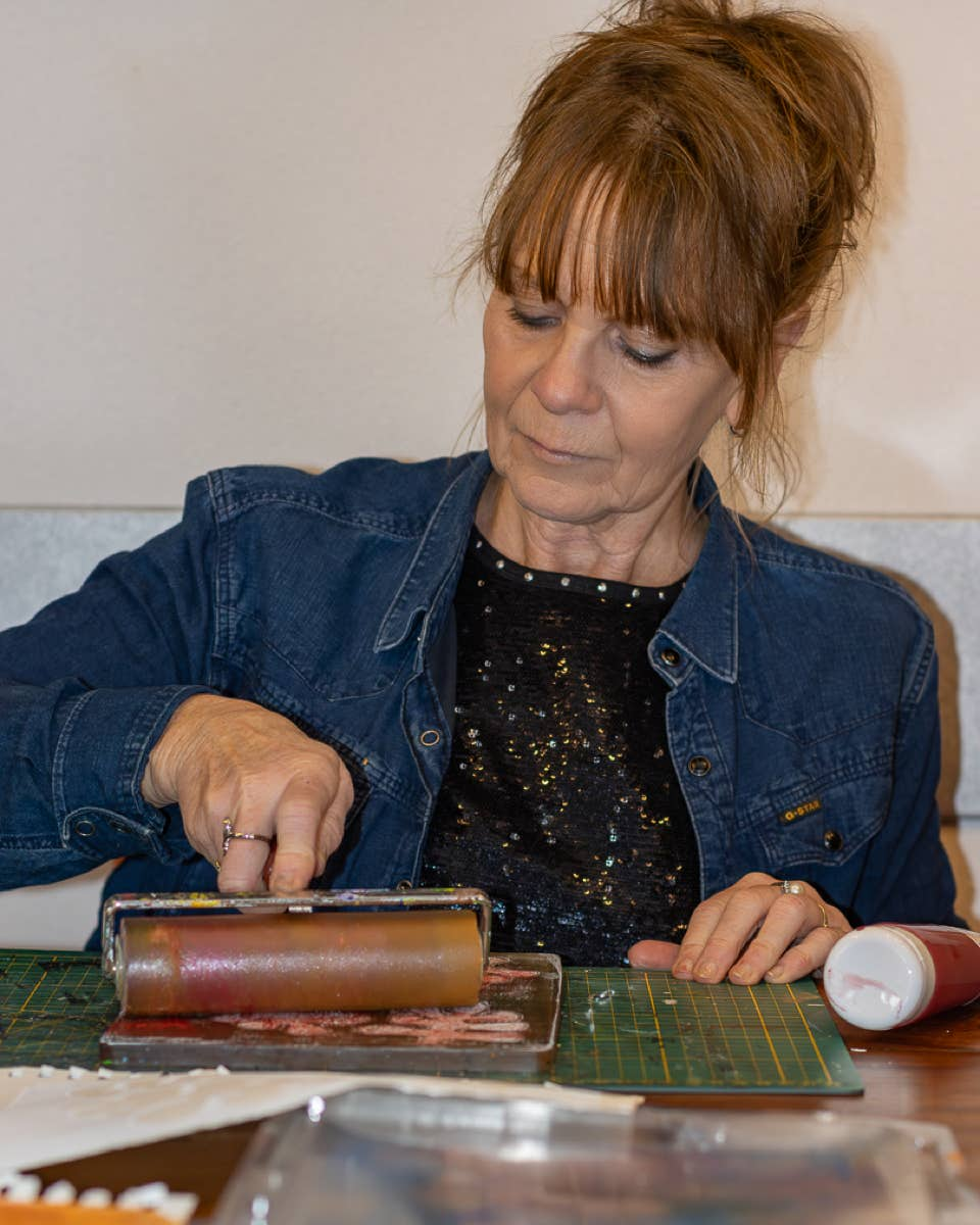 Lisette Boer bezig met een roller op een door haar gemaakte monoprint.