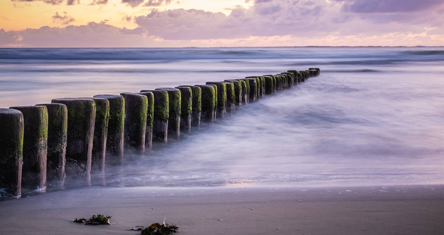 Foto van golfbrekers die vanaf het strand de zee in lopen.