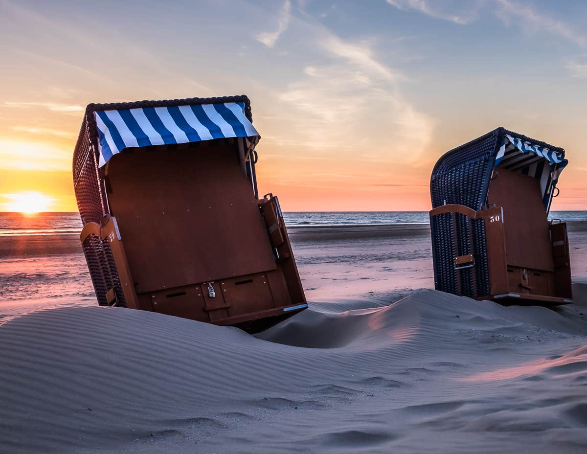 Foto van verlaten strandstoelen op het strand bij zonsondergang.